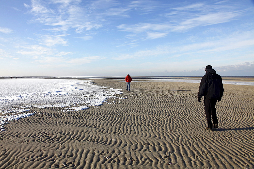 People walking along the snow-covered beach on the East Frisian North Sea island of Spiekeroog, Lower Saxony, Germany, Europe