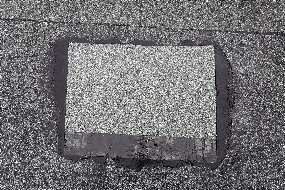 Patched-up, repaired area on a roof made of roofing felt