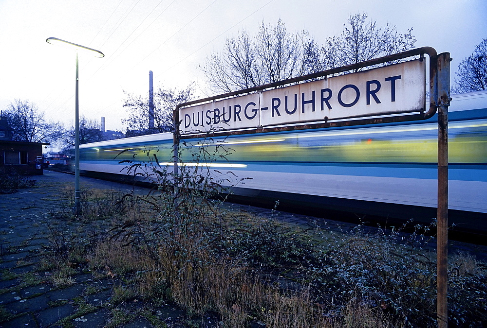 Overgrown platform, train passing, Duisburg-Ruhrort suburban train station, North Rhine-Westphalia, Germany, Europe