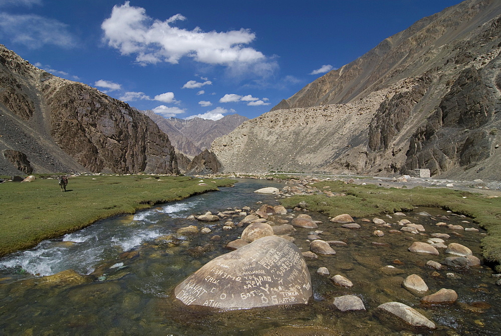 Inscriptions on a rock in the river flowing through Madyian Valley, Pamir Mountains, Tajikistan, Central Asia