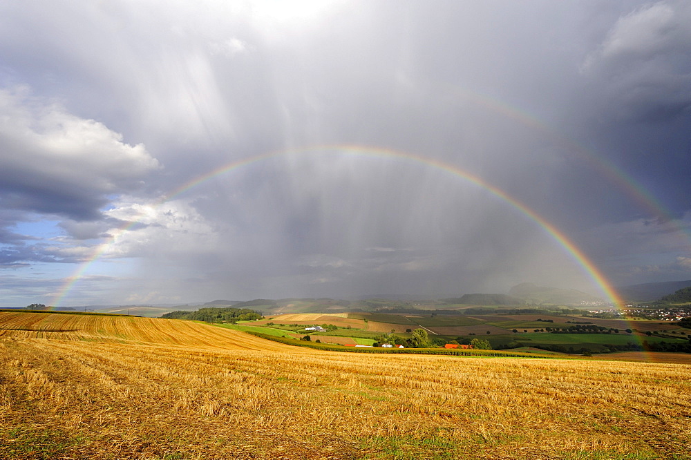 View over a stubble field with rainbow, Hegau region, Landkreis Konstanz county, Baden-Wuerttemberg, Germany, Europe