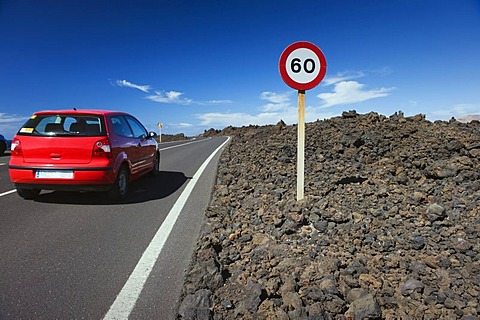 Red car on a road, volcanic landscape at Los Hervideros, Timanfaya National Park, Lanzarote, Canary Islands, Spain, Europe