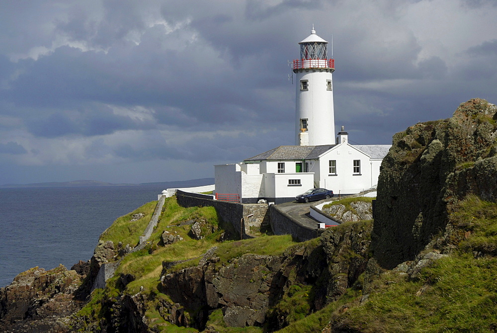 Fanad Head Lighthouse on rocky cliff, rain shower, County Donegal, Ireland, Europe