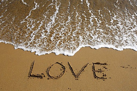 "Love" written in the sand on the beach