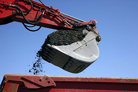 Excavator shovel, laden with soil, construction site