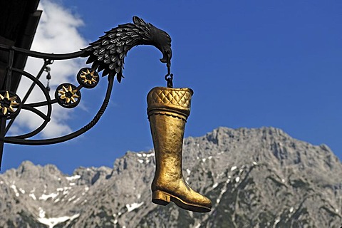 Hanging boot with eagle as an advertising sign of a shoe store, int he back the Karwendelgebirge mountains, Hochstrasse 8, Mittenwald, Upper Bavaria, Bavaria, Germany, Europe