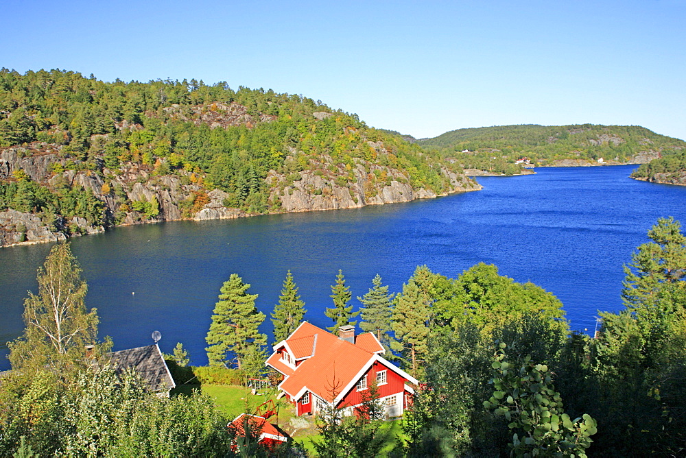 Red wooden house on a fjord near Risor, Scandinavia, Norway, Europe