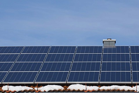 Solar panels on the roof of a house with patches of snow, renewable energy