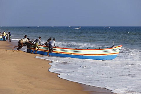 Fishermen pushing their fishing boat into the sea, Somatheeram Beach, Malabarian Coast, Malabar, Kerala state, India, Asia