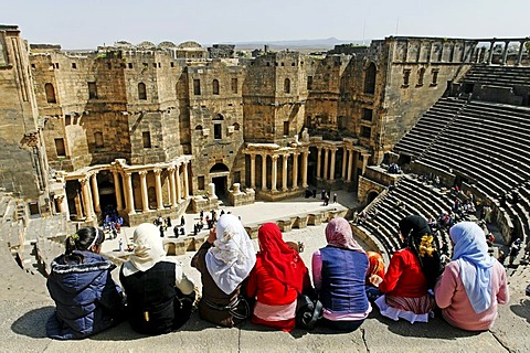 Girls with headscarves sitting on the stairs in the auditorium, Roman theater in Bosra, Syria, Asia