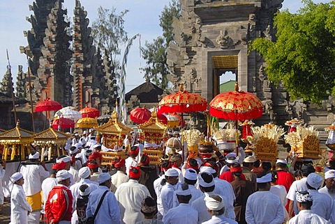 Balinese Hinduism, gathering of believers, ceremony, believers in bright temple dress carrying red parasols and shrines, temple tower and in the back the split gate, Candi bentar, Pura Ulun Danu Batur temple, Batur village, Bali, Indonesia, Southeast Asia