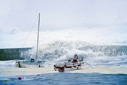 High waves crashing over the harbor wall and small boats, stormy seas on the Brittany coast, hurricane, Finistere, Brittany, France, Europe