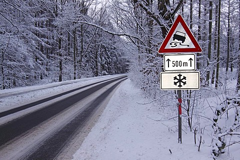 Warning signs in winter, road signs warning of danger of skidding on black ice, and snow on icy road in the forest, Tangstedt, Schleswig-Holstein, Germany, Europe