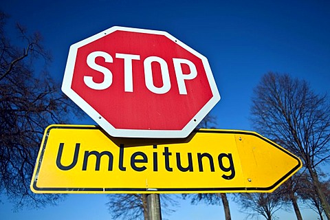 Stop sign and German diversion sign against a blue sky