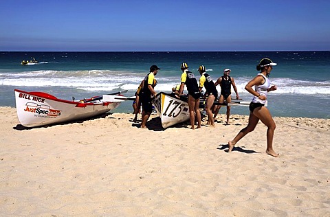 Competition Surf boats and a female Surf Life Saver running on, Scarborough Beach, Perth, Western Australia, Australia