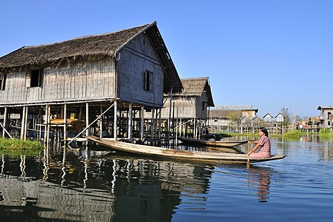 Woman in row boat in front of pile dwellings, Inle Lake, Burma, Myanmar, Southeast Asia