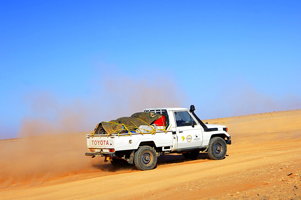 Jeep at high speed on a desert road, Sahara, Libya, Africa