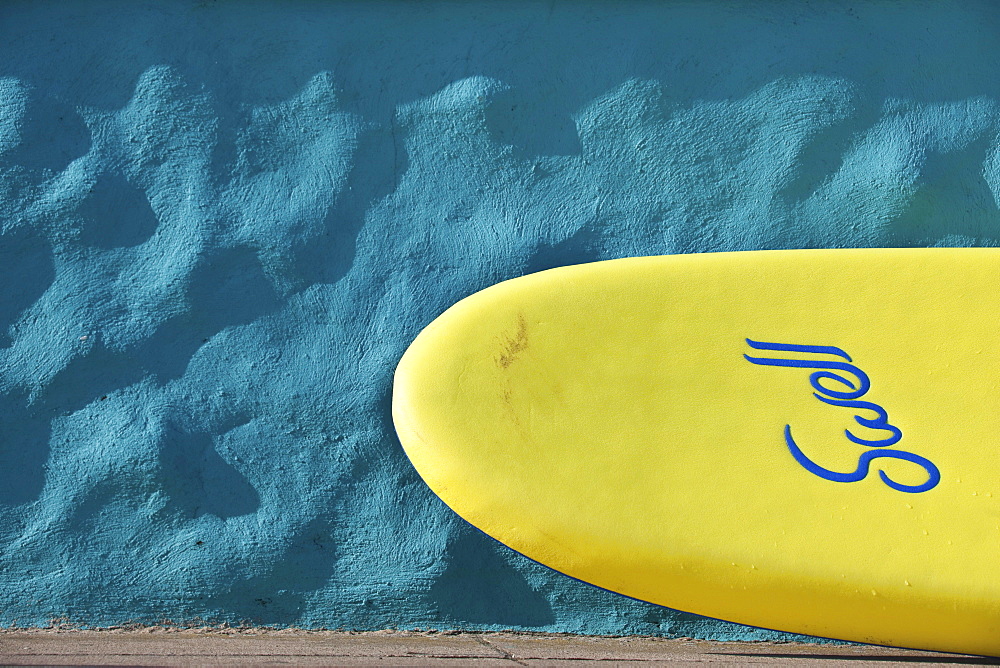 Yellow surfboard in front of a wall, Praa Sands, Cornwall, England, United Kingdom, Europe