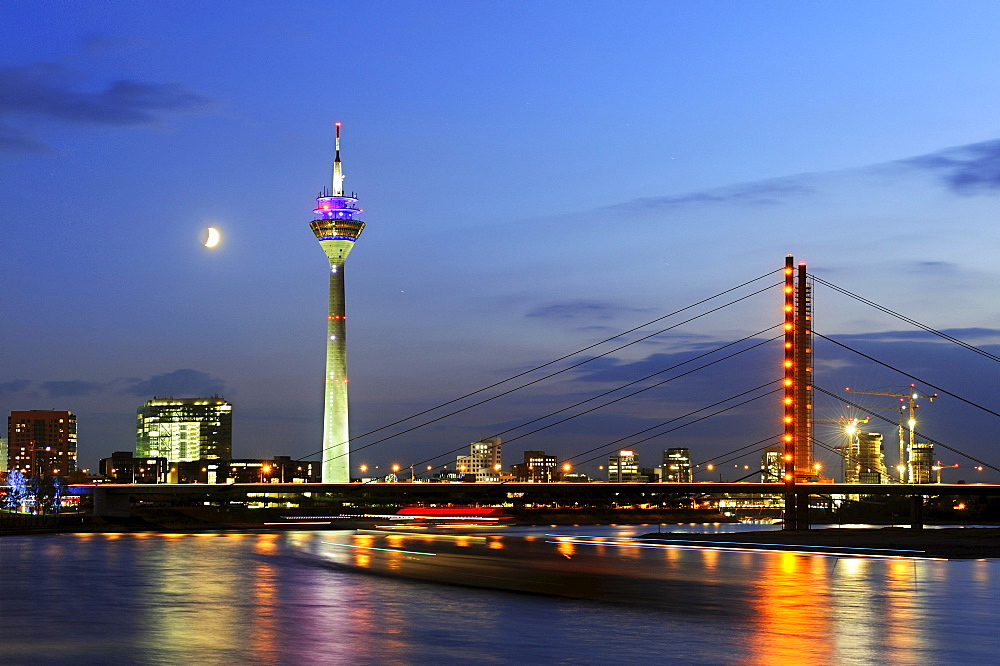 View from the bank of the Rhine River across the Rhine to the skyline of Duesseldorf and the Rheinturm Tower and Rheinkniebruecke bridge, North Rhine-Westphalia, Germany, Europe