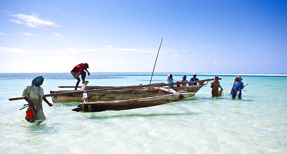 A fishing boat brings brightly dressed women to the beach, Zanzibar, Tanzania, Africa