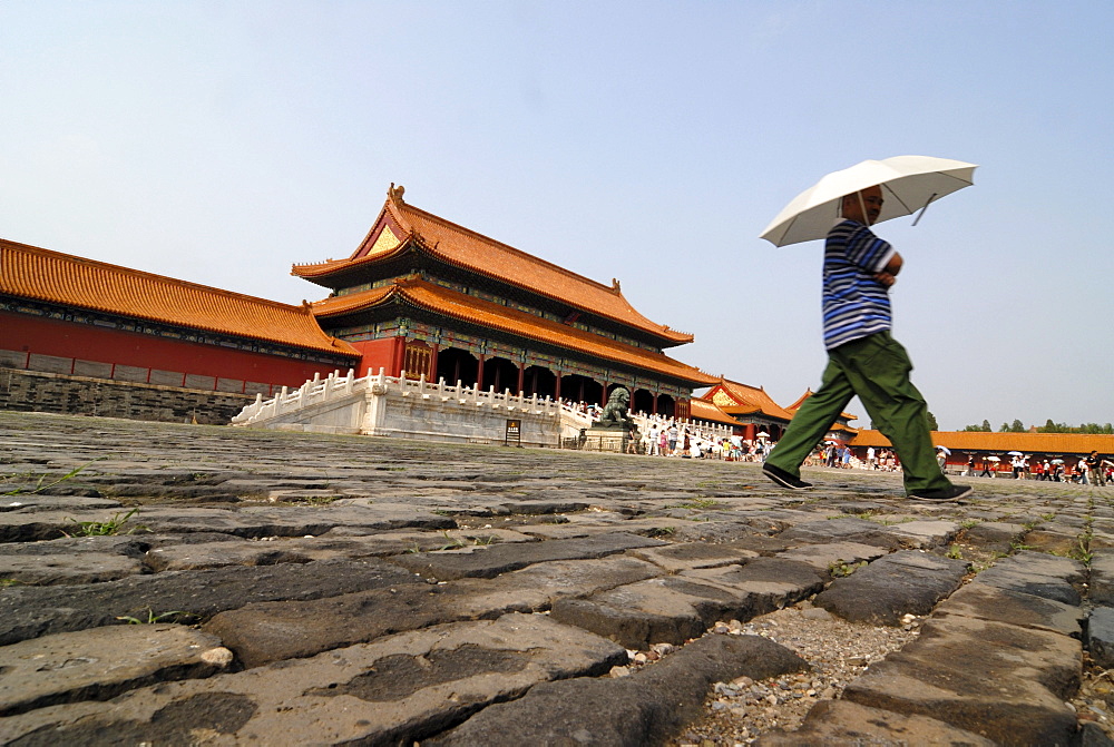 Man with parasol walking over cobblestones, Forbidden City, Imperial Palace, Beijing, China, Asia