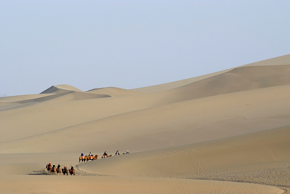 Camel caravan with tourists in front of the sand dunes of the Gobi Desert during the ascent of Mount Mingshan near Dunhuang, Silk Road, Gansu, China, Asia