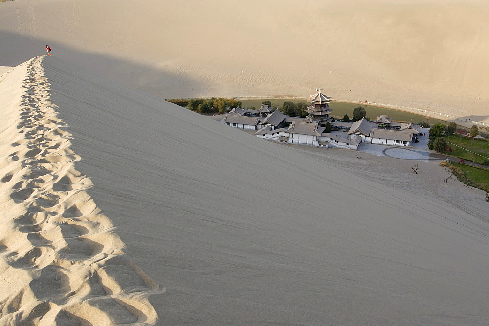 View from the sand dunes of the Gobi Desert to the Crescent Lake with a Chinese pagoda near Dunhuang, Silk Road, Gansu, China, Asia