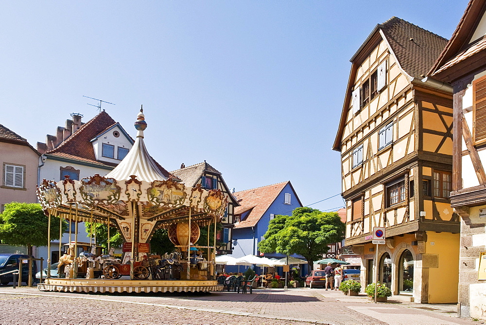 Carousel in front of half-timbered houses in the historic town of Obernai, Alsace, France, Europe