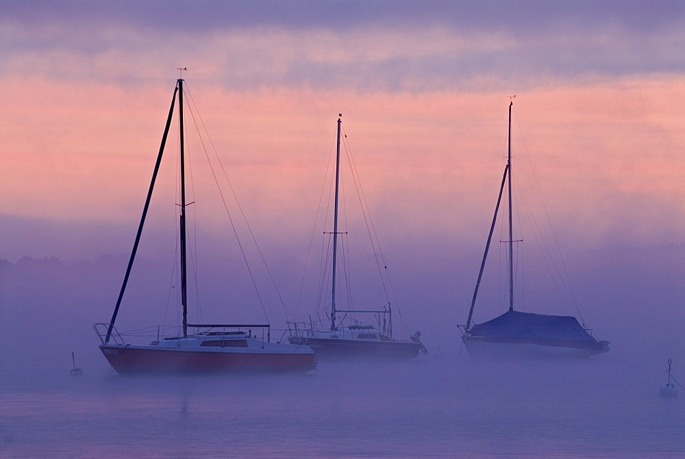 Sun rising behind sailing boats and fog over Ammersee lake, Bavaria, Germany, Europe