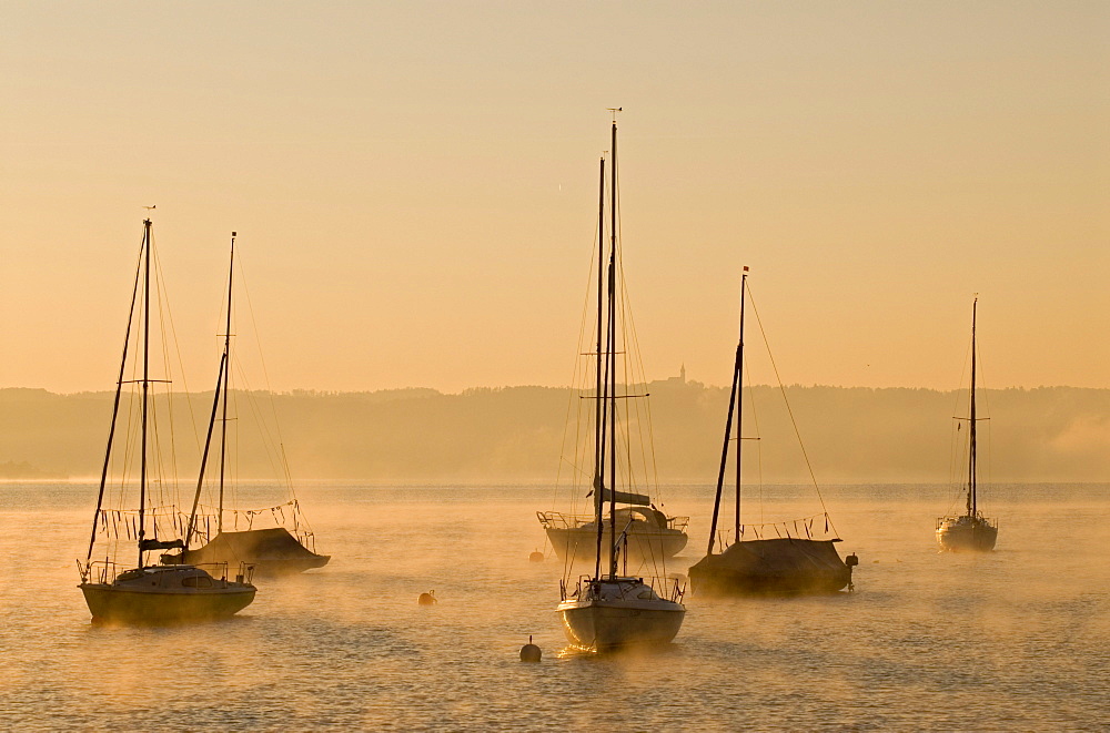 Sailing boats and low morning fog over Ammersee lake at Utting, Bavaria, Germany, Europe