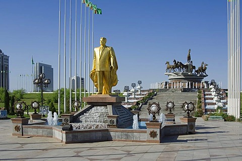 Gold covered statue of President Turkmenbasy in front of the monument of the 10th anniversary of Independence and Akhal-teke horses fountain, Ashgabat, Turkmenistan