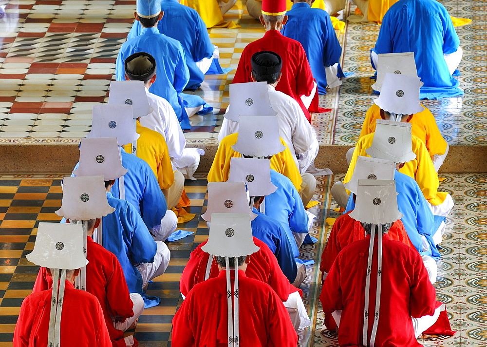 Monks and nuns, colorful robes in red, yellow, blue, praying, ceremonial midday prayer in the Cao Dai temple, Tay Ninh, Vietnam, Asia