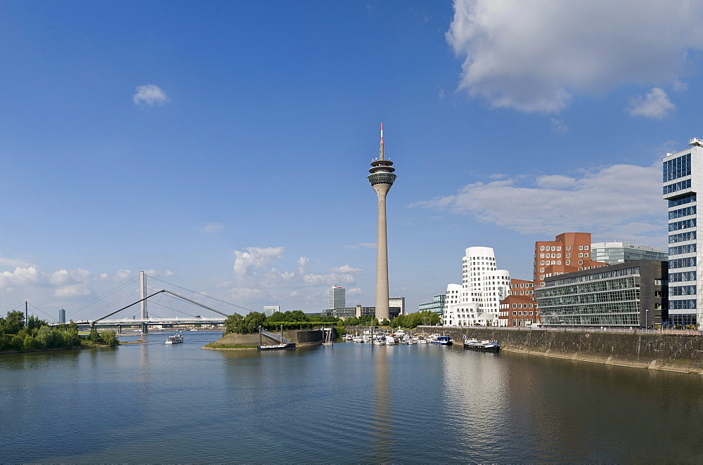 Panoramic view, Duesseldorf Medienhafen media port, Neuer Zollhof with "Dancing Office Buildings" by F.O. Gehry, Rheinturm tower and Landtag parliament, Oberkasseler Bruecke bridge, in the front sport boats at the pier and water, Duesseldorf, state capita