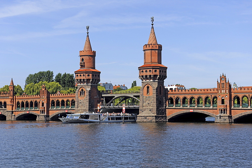 Oberbaumbruecke bridge with passenger ships on the Spree river Berlin, Germany, Europe