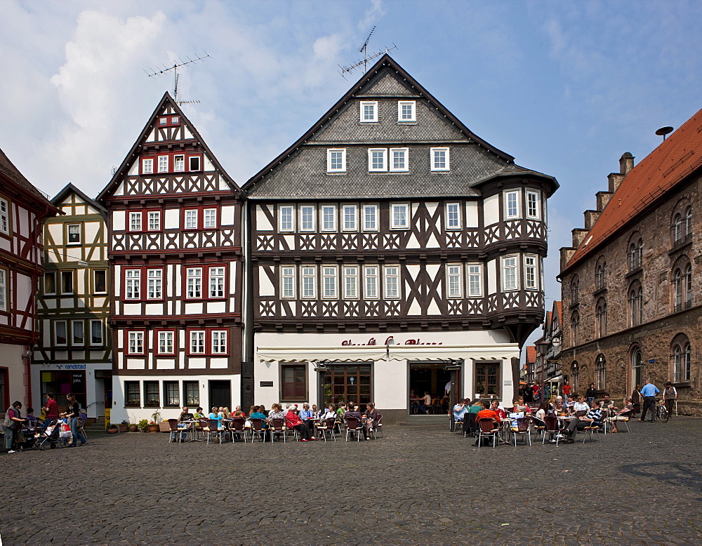 Tourists sitting in the sun on the market square in front of a coffeehouse, historic town, Alsfeld, Hesse, Germany, Europe