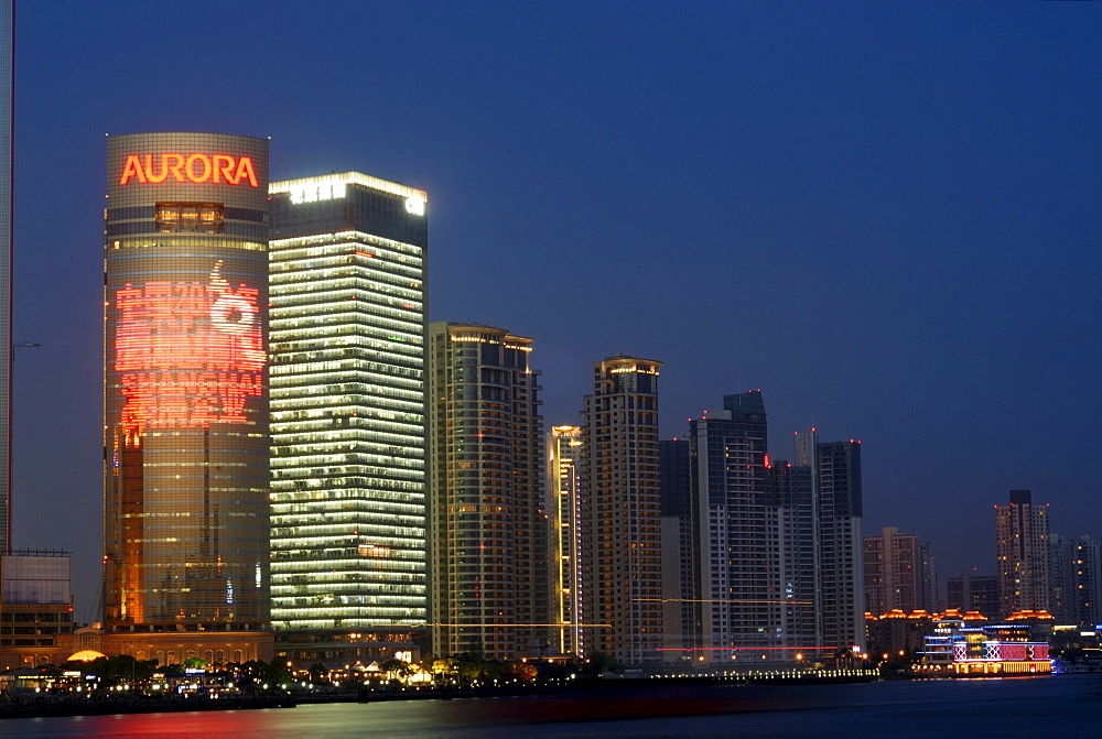 Illuminated skyline with neon signs of the Chinese financial district of Pudong in Shanghai with Huangpu River, Shanghai, China