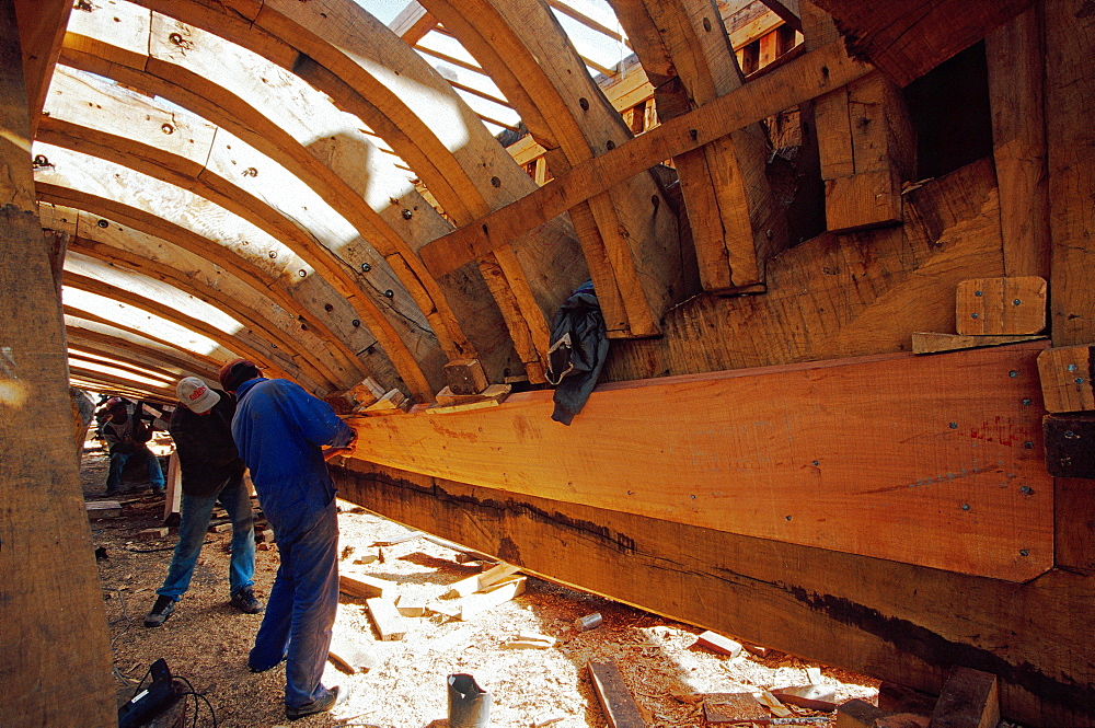 Shipwright under the hull of a trawler in the shipyard of Essaouira, Morocco, North Africa