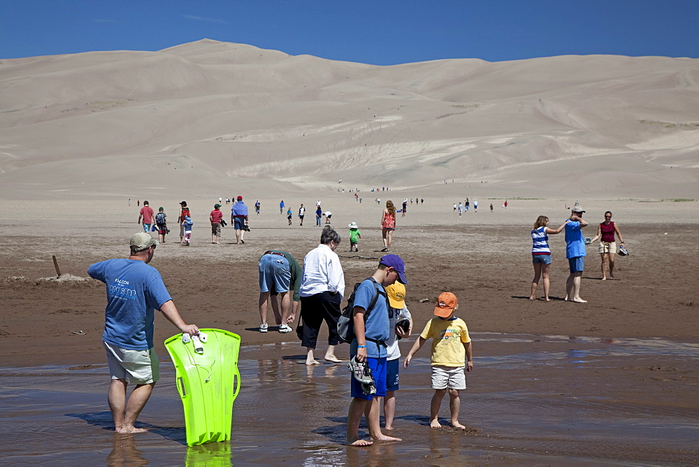 Vacationers along Medano Creek in Great Sand Dunes National Park, Mosca, Colorado, USA