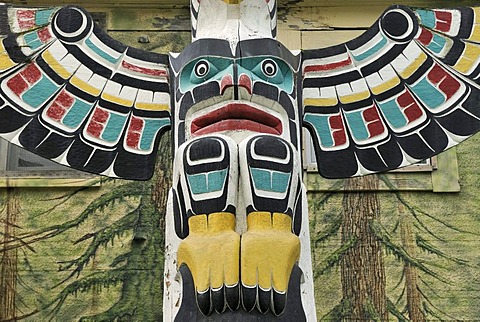 Totem pole of the Cowichan Indians, close-up, in front of a painted house wall, Duncan, Vancouver Island, Canada, North America