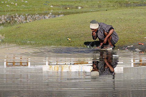 Indian migrant worker for roadworks washes in the morning on the outskirts of the oasis Hundar, Nubra valley, Ladakh, India, Himalayas