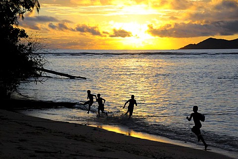 Children playing by the sea at sunset, Anse La Reunion, La Digue, Seychelles