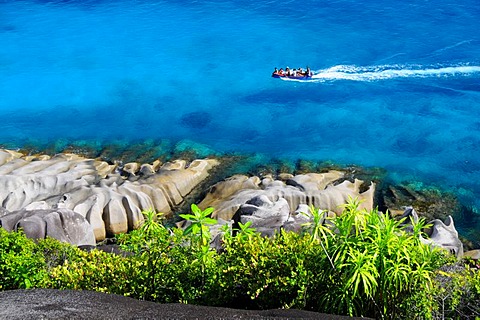 Granite rocks and tropical vegetation in front of a boat on the sea, northwest coast, Mahe, Seychelles