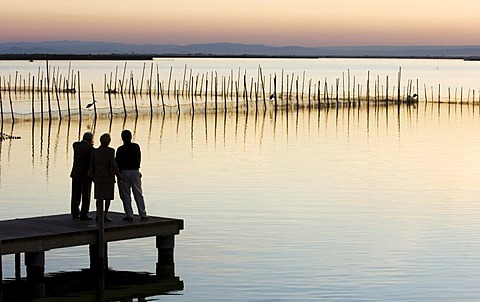 Two men and a woman on a pier, Lake Albufera at sunset, south of Valencia, Spain, Europe