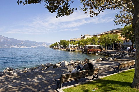 Pensioners sitting on a park bench in Torri del Benaco on Lake Garda, Lago di Garda, Lombardy, Italy, Europe