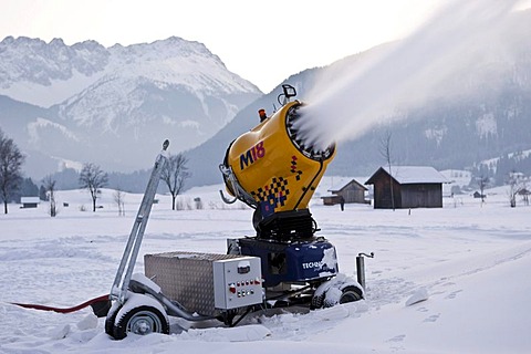 Snow cannon spraying snow into a valley between Ehrwald and Lermoos at dusk, Tyrol, Austria, Europe