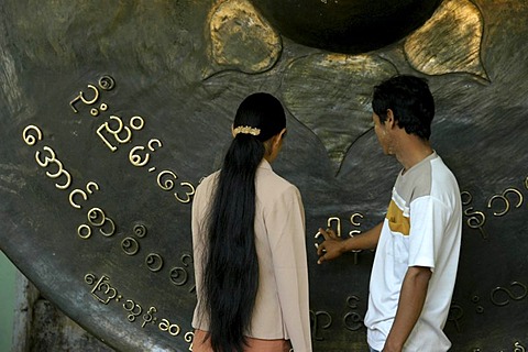 Couple wishing for future luck, touching large brass gong, Burmese scripture, Mandalay, Birma, Burma, Myanmar, South Asia