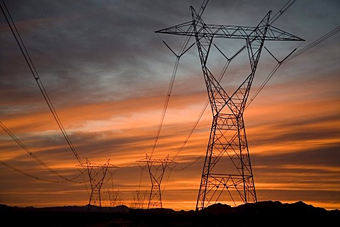 An electrical power line is silhouetted against the sunset in the Sonoran Desert, Palo Verde, Arizona, USA