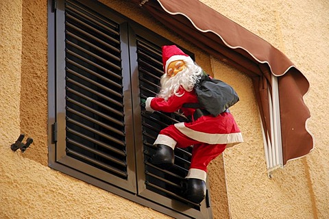 Santa Claus climbs up a window shutter, Polop, Costa Blanca, Spain