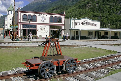 A handcar in front of historical wooden buildings in the gold rush town of Skagway Alaska USA