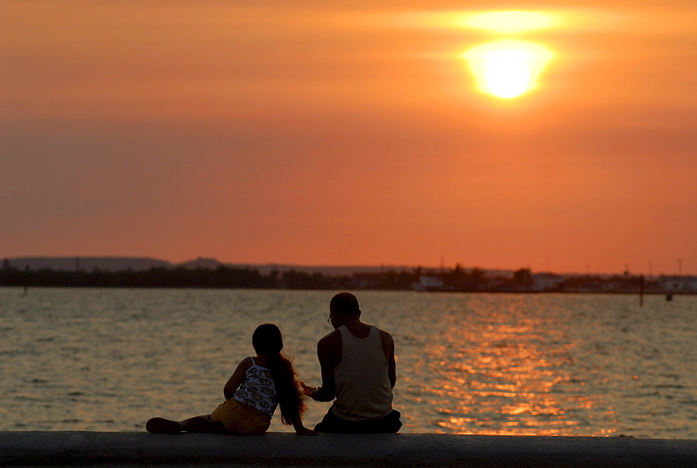 Man and child sitting on the malecon at sunset, Cienfuegos, Cuba, Americas